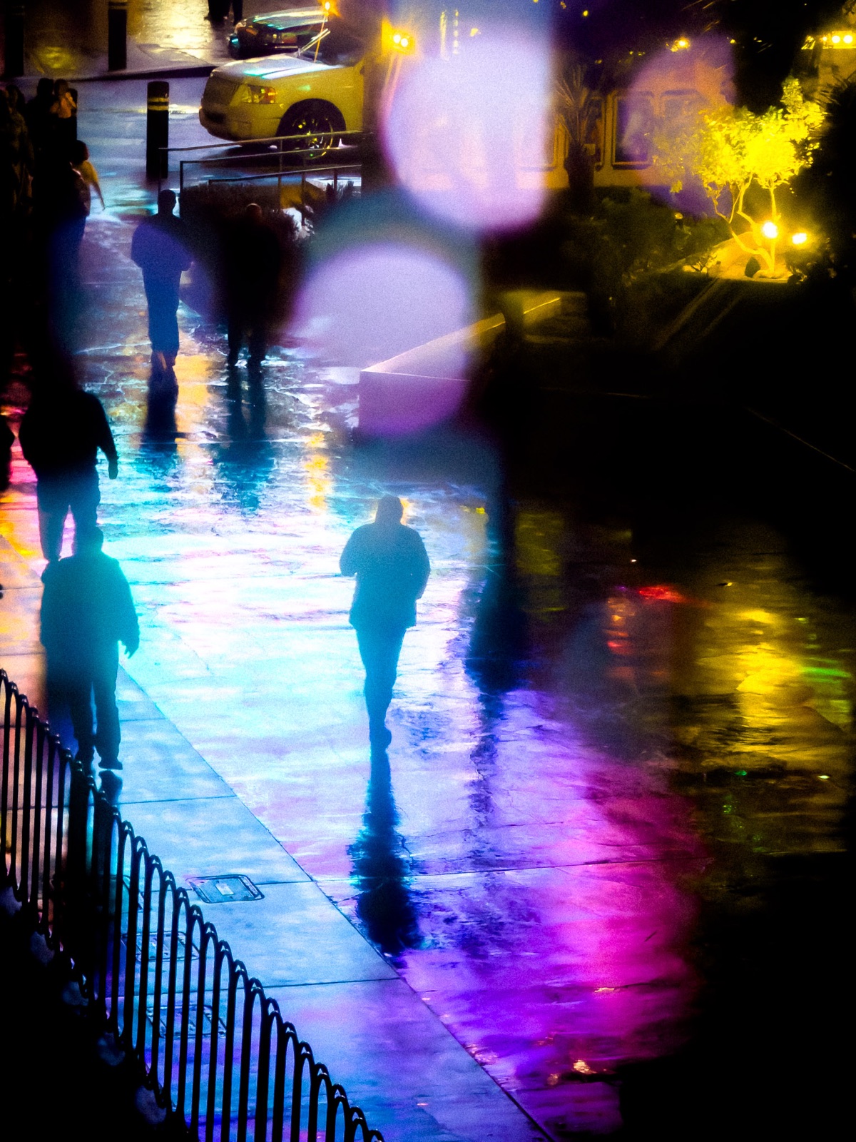 City sidewalk at night reflecting neon signage